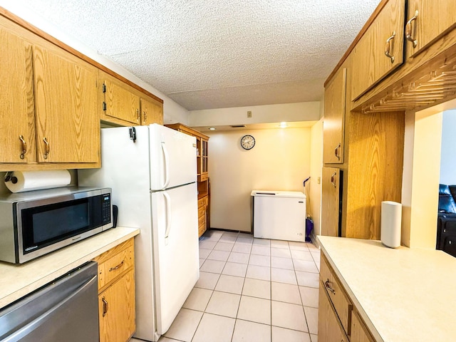 3658 Alder Dr Unit D1, West Palm Beach, FL 33417 - kitchen featuring stainless steel appliances, light countertops, light tile patterned floors, a textured ceiling, and brown cabinets