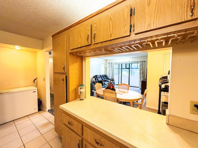 3658 Alder Dr Unit D1, West Palm Beach, FL 33417 - kitchen featuring light countertops, brown cabinets, light tile patterned floors, and a textured ceiling