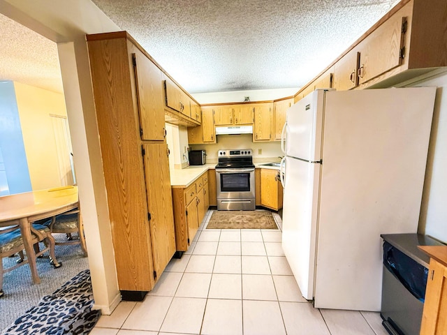 3658 Alder Dr Unit D1, West Palm Beach, FL 33417 - kitchen featuring stainless steel appliances, under cabinet range hood, a textured ceiling, light countertops, and light tile patterned floors