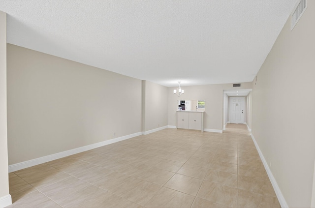 5574 Witney Dr Unit 104, Delray Beach, FL 33484 - empty room with a chandelier, light tile patterned floors, and a textured ceiling