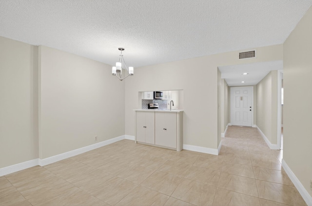 5574 Witney Dr Unit 104, Delray Beach, FL 33484 - empty room featuring a chandelier, light tile patterned floors, a textured ceiling, and recessed lighting