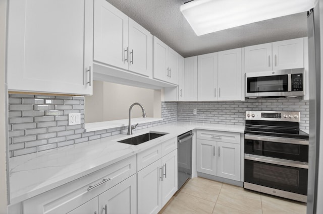5574 Witney Dr Unit 104, Delray Beach, FL 33484 - kitchen with appliances with stainless steel finishes, light tile patterned flooring, white cabinets, and a textured ceiling