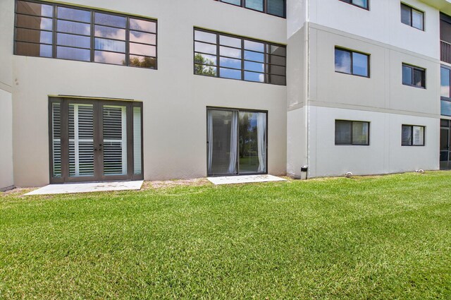 5574 Witney Dr Unit 104, Delray Beach, FL 33484 - rear view of property featuring stucco siding and a lawn