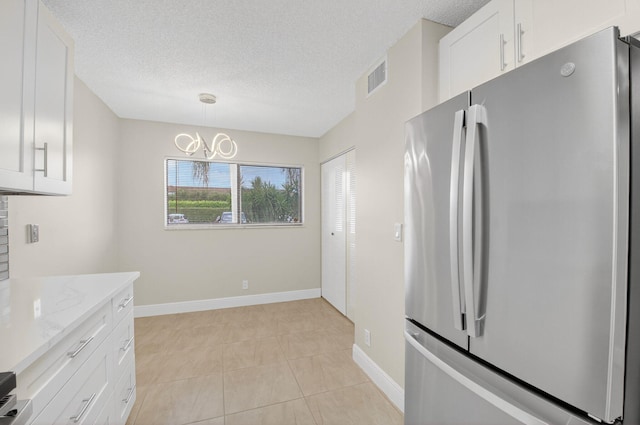 5574 Witney Dr Unit 104, Delray Beach, FL 33484 - kitchen featuring freestanding refrigerator, white cabinets, a chandelier, light stone countertops, and a textured ceiling