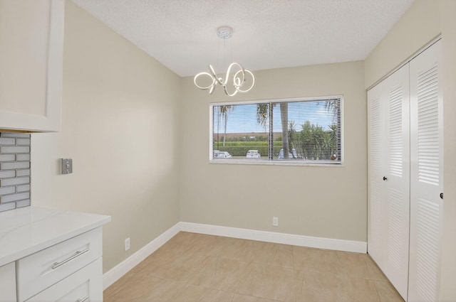 5574 Witney Dr Unit 104, Delray Beach, FL 33484 - unfurnished dining area featuring a chandelier, a textured ceiling, and light tile patterned flooring