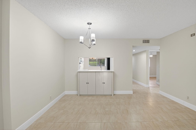 5574 Witney Dr Unit 104, Delray Beach, FL 33484 - spare room featuring a textured ceiling, a chandelier, and light tile patterned flooring