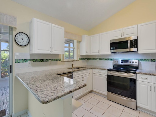374 NW Sherry Ln, Port Saint Lucie, FL 34986 - kitchen featuring appliances with stainless steel finishes, vaulted ceiling, white cabinetry, a peninsula, and tasteful backsplash