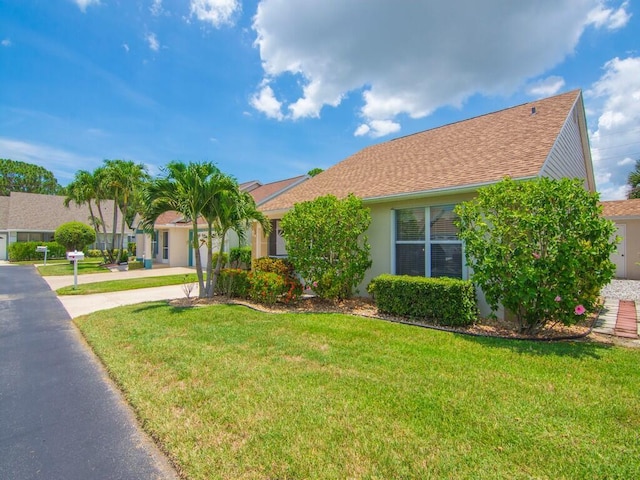 374 NW Sherry Ln, Port Saint Lucie, FL 34986 - view of front facade featuring a front lawn, stucco siding, and roof with shingles