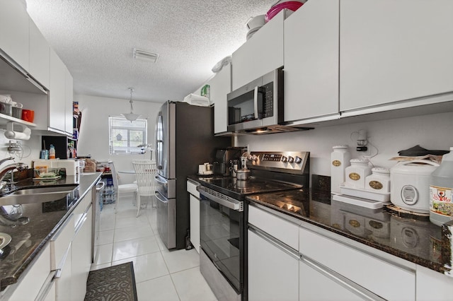 14085 Nesting Way Unit C, Delray Beach, FL 33484 - kitchen featuring stainless steel appliances, white cabinets, a textured ceiling, dark stone countertops, and light tile patterned flooring