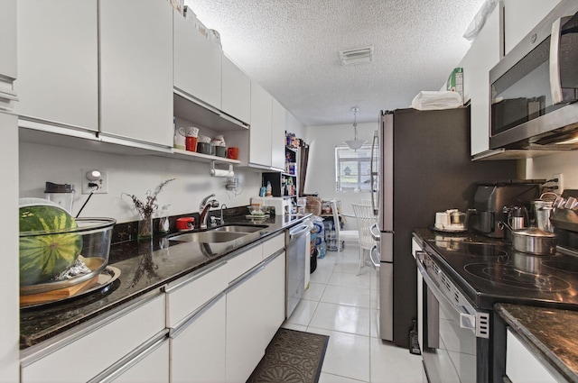 14085 Nesting Way Unit C, Delray Beach, FL 33484 - kitchen with stainless steel appliances, white cabinetry, a textured ceiling, and dark stone counters