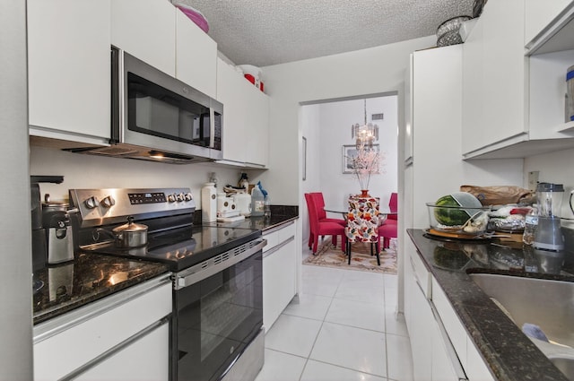 14085 Nesting Way Unit C, Delray Beach, FL 33484 - kitchen featuring appliances with stainless steel finishes, white cabinets, light tile patterned flooring, a textured ceiling, and dark stone countertops