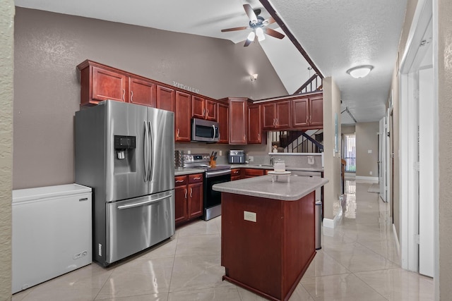 7670 NW 79th Ave Unit O3, Tamarac, FL 33321 - kitchen with appliances with stainless steel finishes, reddish brown cabinets, a ceiling fan, vaulted ceiling, and light countertops