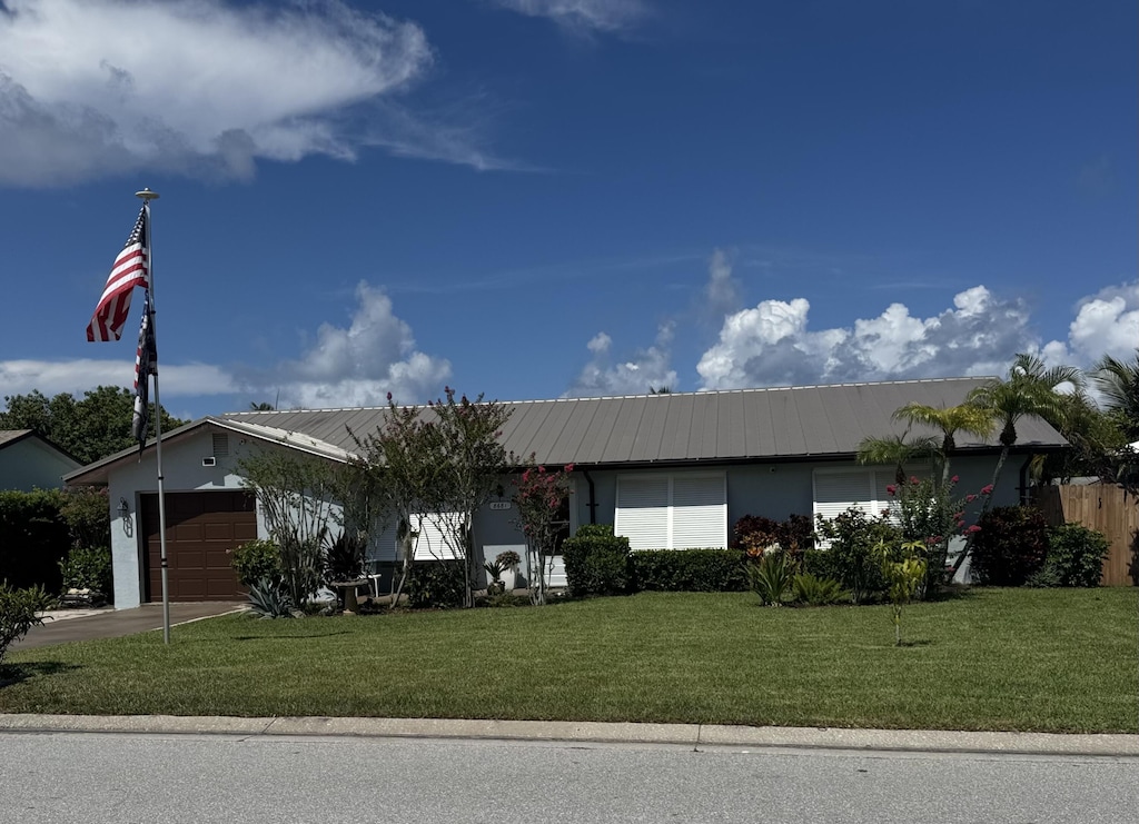 8681 SE Eagle Ave, Hobe Sound, FL 33455 - ranch-style home with an attached garage, a metal roof, a front yard, stucco siding, and driveway