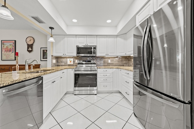 11265 Bannock Ave Unit 5, Boynton Beach, FL 33437 - kitchen with stainless steel appliances, white cabinets, hanging light fixtures, tasteful backsplash, and light stone countertops