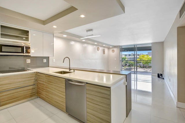 3600 NE 170th St Unit 407, North Miami Beach, FL 33160 - kitchen featuring appliances with stainless steel finishes, modern cabinets, a peninsula, light tile patterned flooring, and a wall of windows