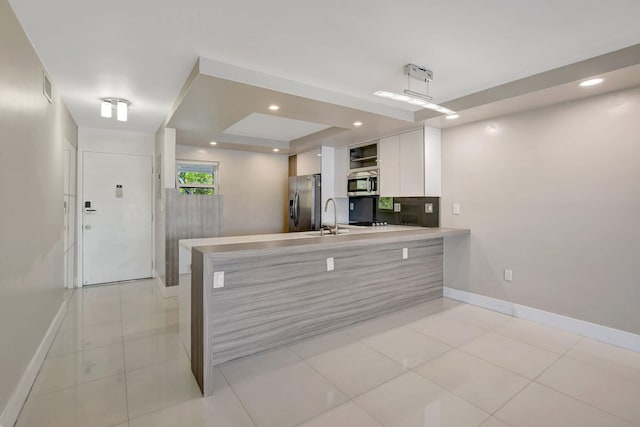 3600 NE 170th St Unit 407, North Miami Beach, FL 33160 - kitchen with stainless steel appliances, white cabinets, a peninsula, recessed lighting, and a raised ceiling