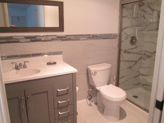 14572 Canalview Dr Unit C, Delray Beach, FL 33484 - bathroom featuring a marble finish shower, vanity, tile walls, and a wainscoted wall