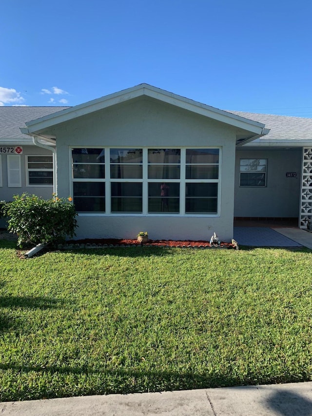 14572 Canalview Dr Unit C, Delray Beach, FL 33484 - view of property exterior featuring a lawn, stucco siding, a patio area, and a shingled roof