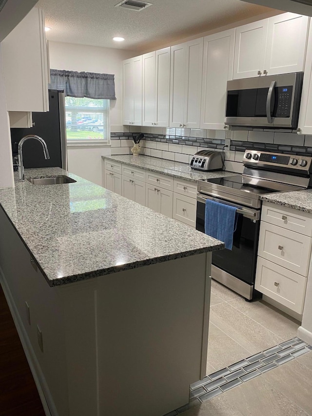 14572 Canalview Dr Unit C, Delray Beach, FL 33484 - kitchen featuring appliances with stainless steel finishes, white cabinets, tasteful backsplash, light stone counters, and recessed lighting