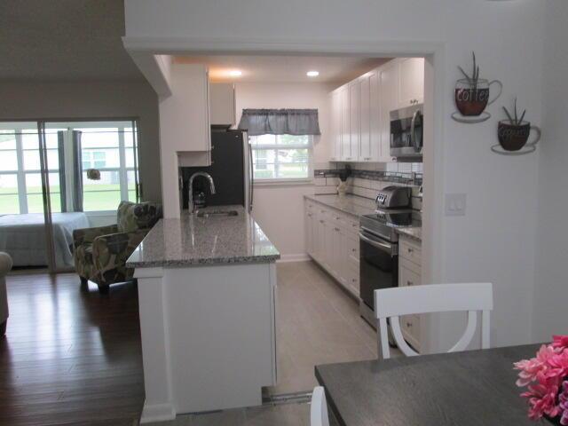 14572 Canalview Dr Unit C, Delray Beach, FL 33484 - kitchen with appliances with stainless steel finishes, white cabinetry, tasteful backsplash, light stone countertops, and recessed lighting