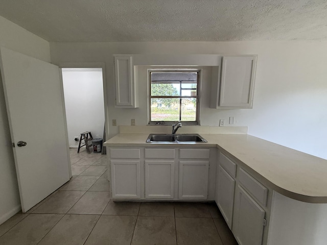 2564 Navajo Ave, Fort Pierce, FL 34946 - kitchen with white cabinetry, light tile patterned floors, light countertops, a textured ceiling, and a peninsula