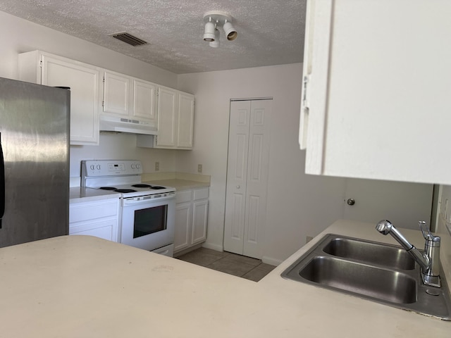 2564 Navajo Ave, Fort Pierce, FL 34946 - kitchen with white electric stove, under cabinet range hood, freestanding refrigerator, white cabinetry, and tile patterned flooring
