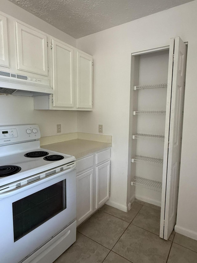 2564 Navajo Ave, Fort Pierce, FL 34946 - kitchen featuring white range with electric stovetop, under cabinet range hood, light tile patterned floors, white cabinets, and a textured ceiling