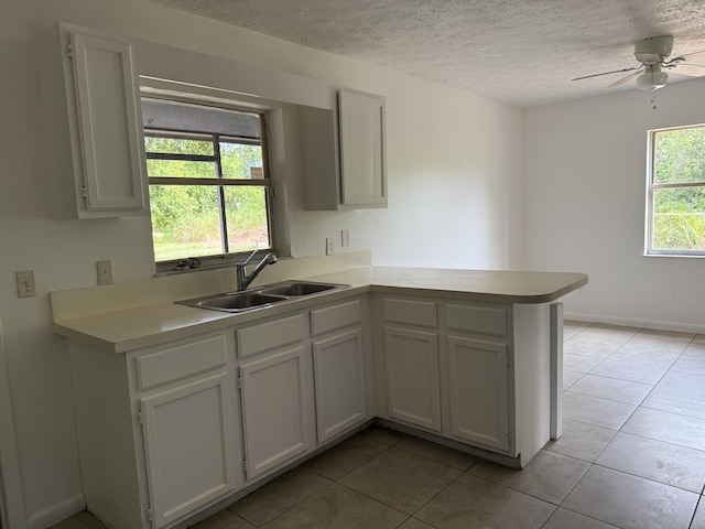 2564 Navajo Ave, Fort Pierce, FL 34946 - kitchen with a peninsula, light tile patterned floors, light countertops, a textured ceiling, and a ceiling fan