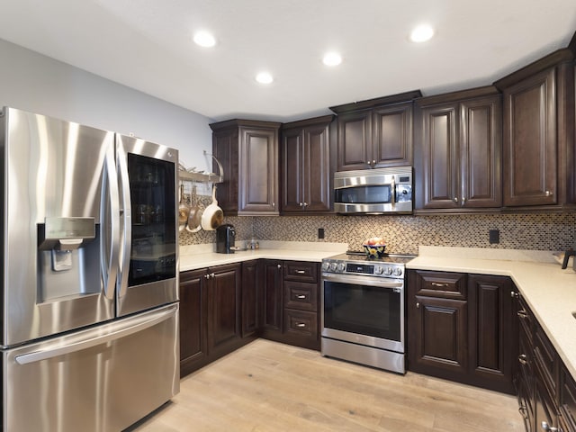 1155 Woodcrest Rd W, West Palm Beach, FL 33417 - kitchen featuring stainless steel appliances, dark brown cabinetry, light countertops, light wood-style flooring, and backsplash