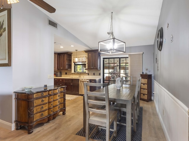 1155 Woodcrest Rd W, West Palm Beach, FL 33417 - dining area featuring lofted ceiling, light wood-style flooring, a chandelier, and a wainscoted wall