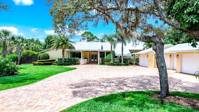 1819 SW Crane Crk, Palm City, FL 34990 - view of front of home featuring decorative driveway, french doors, an attached garage, and a metal roof
