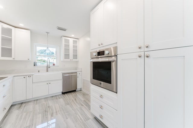 450 NE 38th St, Boca Raton, FL 33431 - kitchen featuring stainless steel appliances, glass insert cabinets, light countertops, white cabinets, and decorative light fixtures