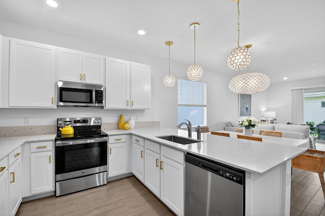 14929 Three Ponds Trl, Delray Beach, FL 33446 - kitchen with appliances with stainless steel finishes, a peninsula, open floor plan, light wood finished floors, and recessed lighting
