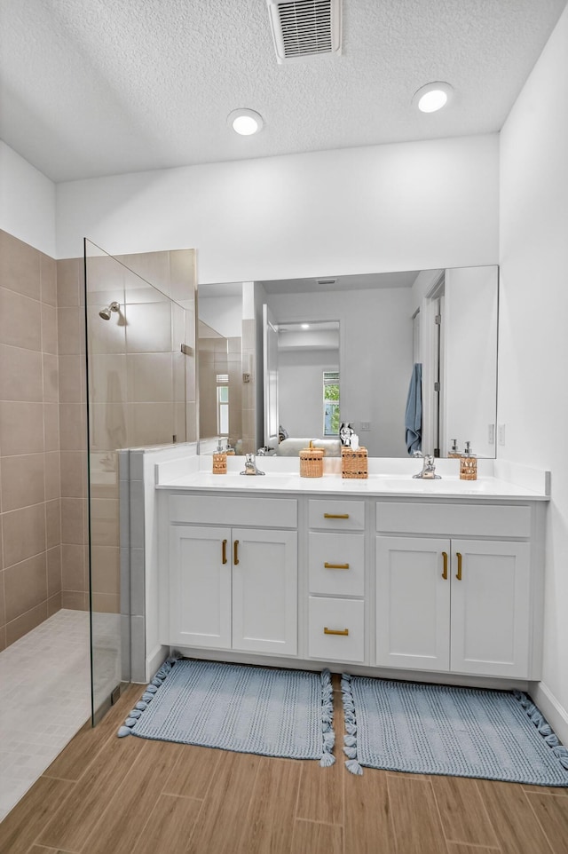 14929 Three Ponds Trl, Delray Beach, FL 33446 - bathroom with wood tiled floors, a walk in shower, a textured ceiling, and double vanity