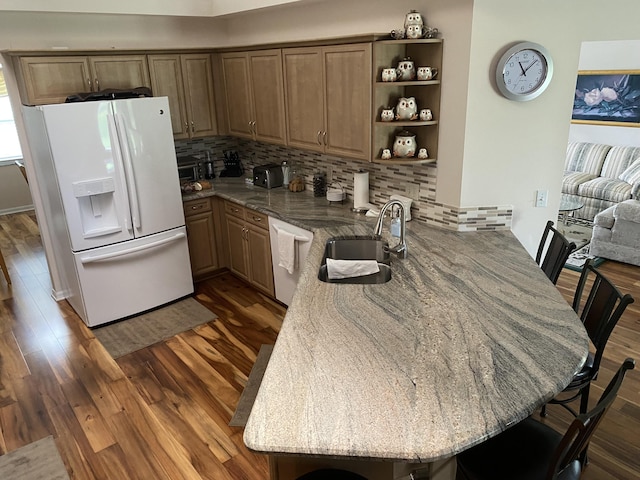 3053 SE Darien Rd, Port Saint Lucie, FL 34952 - kitchen featuring white refrigerator with ice dispenser, a peninsula, dishwasher, a kitchen bar, and dark wood-style floors