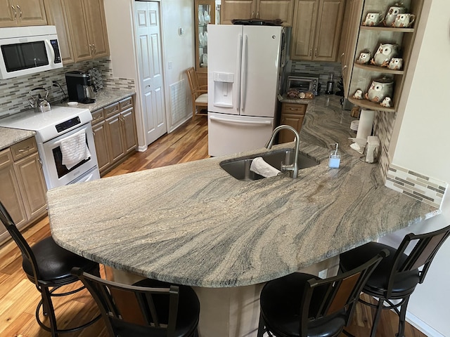3053 SE Darien Rd, Port Saint Lucie, FL 34952 - kitchen with white appliances, decorative backsplash, a kitchen bar, light wood-type flooring, and open shelves