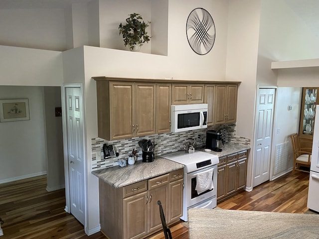 3053 SE Darien Rd, Port Saint Lucie, FL 34952 - kitchen with white microwave, stainless steel electric stove, high vaulted ceiling, dark wood-type flooring, and tasteful backsplash
