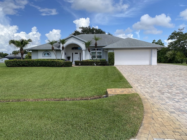3053 SE Darien Rd, Port Saint Lucie, FL 34952 - ranch-style house featuring stucco siding, an attached garage, decorative driveway, a front lawn, and a shingled roof