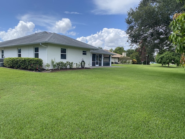 3053 SE Darien Rd, Port Saint Lucie, FL 34952 - back of property featuring a yard, stucco siding, a sunroom, and a shingled roof