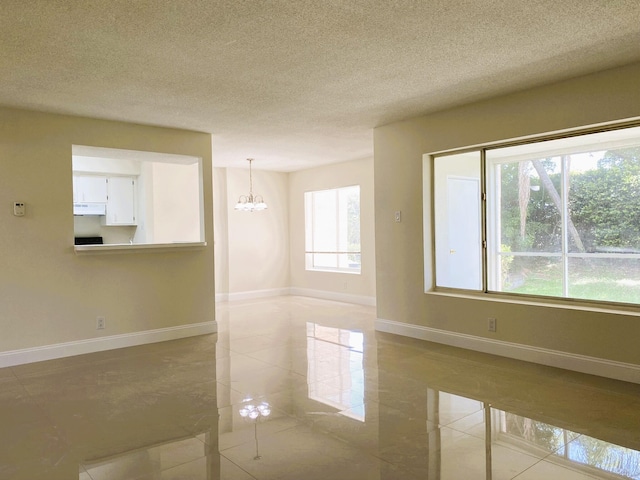 815 W Boynton Beach Blvd Unit 7-102, Boynton Beach, FL 33426 - empty room featuring a chandelier, a textured ceiling, and light tile patterned floors