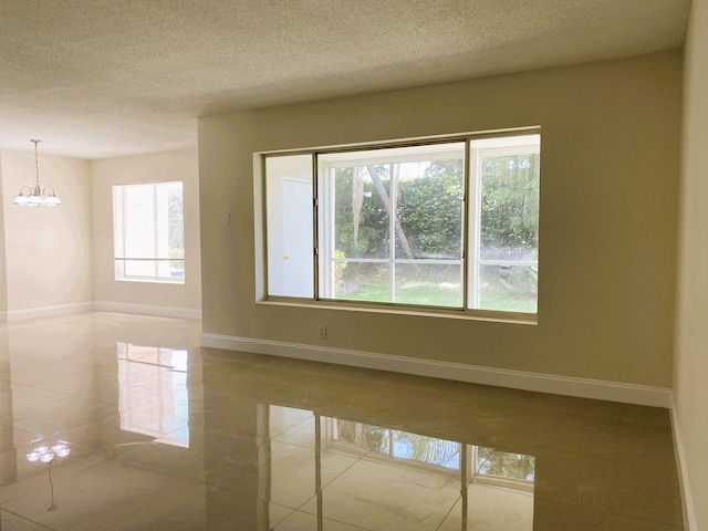 815 W Boynton Beach Blvd Unit 7-102, Boynton Beach, FL 33426 - empty room featuring a chandelier, a textured ceiling, and tile patterned flooring