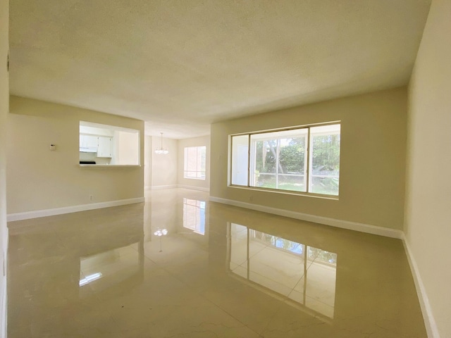 815 W Boynton Beach Blvd Unit 7-102, Boynton Beach, FL 33426 - spare room featuring tile patterned flooring, a textured ceiling, and a chandelier