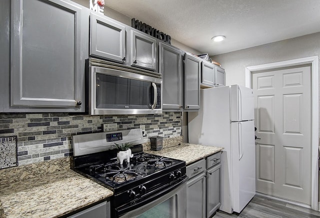 372 NE Ardsley Dr, Port Saint Lucie, FL 34983 - kitchen featuring appliances with stainless steel finishes, gray cabinets, decorative backsplash, wood finished floors, and a textured ceiling