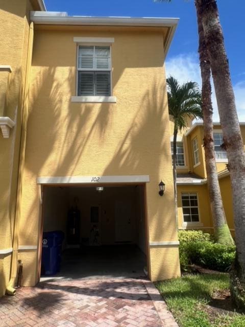 108 W Pigeon Plum Dr W Unit 102, Jupiter, FL 33458 - view of side of property with stucco siding, a garage, and water heater