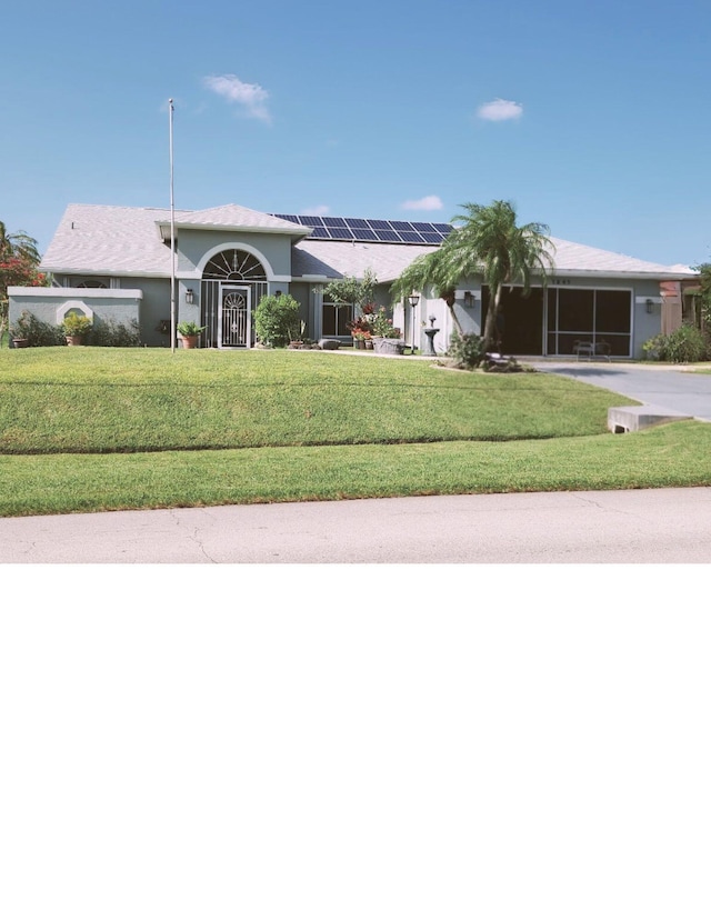 1341 SW Abingdon Ave, Port Saint Lucie, FL 34953 - single story home with roof mounted solar panels, a front yard, driveway, and stucco siding