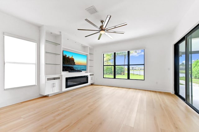 17380 Rainstream Rd, Boca Raton, FL 33496 - unfurnished living room featuring a ceiling fan, light wood-type flooring, a glass covered fireplace, and built in shelves