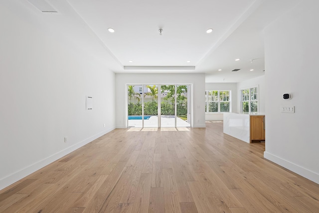 295 Austin Ln, West Palm Beach, FL 33401 - unfurnished living room featuring light wood-style flooring, recessed lighting, and a tray ceiling