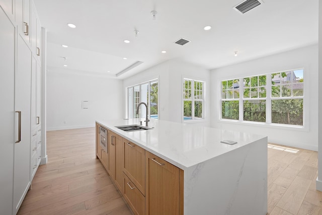 295 Austin Ln, West Palm Beach, FL 33401 - kitchen with recessed lighting, a spacious island, light wood-style flooring, light stone counters, and white cabinetry