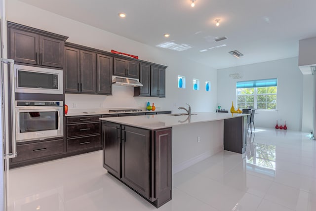 10815 Stellar Cir, Palm Beach Gardens, FL 33412 - kitchen with appliances with stainless steel finishes, light tile patterned floors, under cabinet range hood, an island with sink, and light countertops