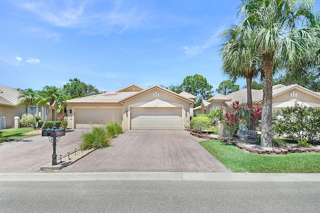 3611 NW Willow Creek Dr, Jensen Beach, FL 34957 - view of front of property featuring a garage, decorative driveway, stucco siding, and a tiled roof